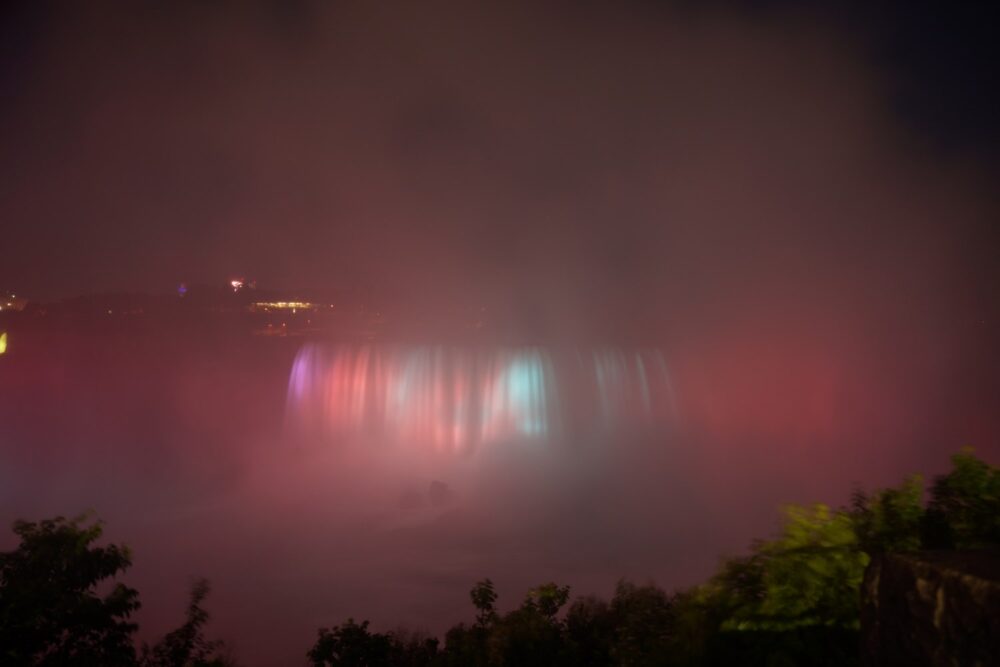 La nuit, les chutes s'éclairent au milieu de la brume.